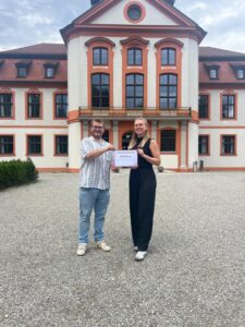 Übergabe des Stipendiums an Maike Körner durch Nikolai Russ aus dem Vorstand des AEJ im Juli 2025